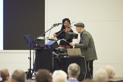 Musikalische Einlage auf der Bühne, eine Frau mit Geige und ein Mann am Schlagzeug.