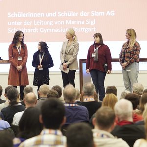 Moderatorin Janine Steeger, links im Bild, spricht mit Umweltministerin Thekla Walker und drei Schülerinnen sowie ihrer Lehrerin und Poetry-Slam-AG-Leiterin.