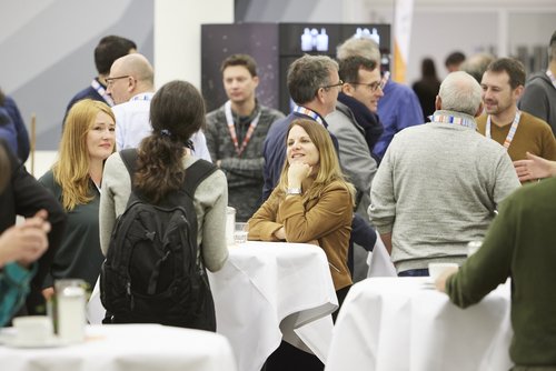 Personen im Gespräch an Stehtischen im Foyer beim Herbstforum Altbau.