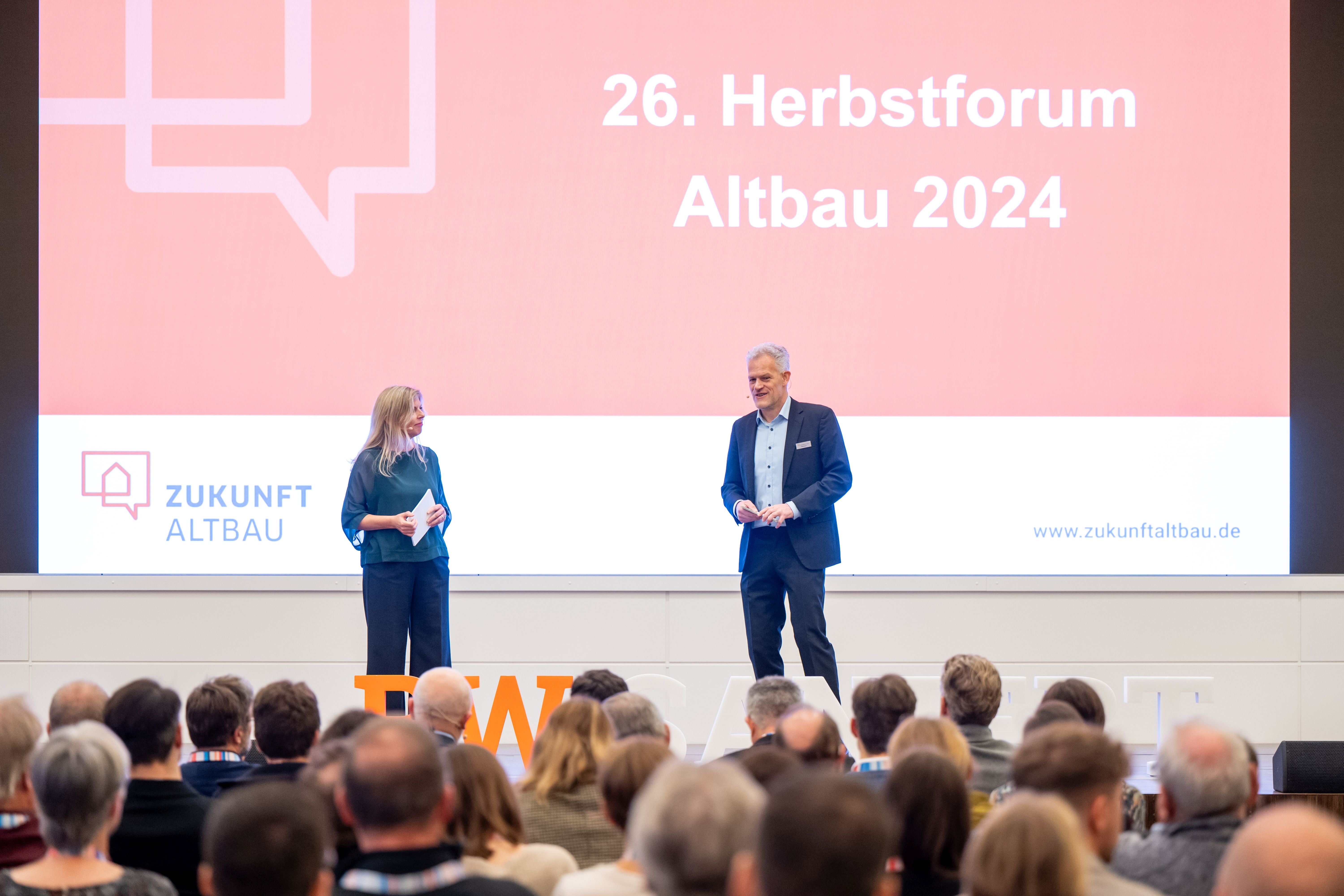Auf der Bühne beim Herbstforum stehen die Moderatoren Natasha Walker und Frank Hettler. 