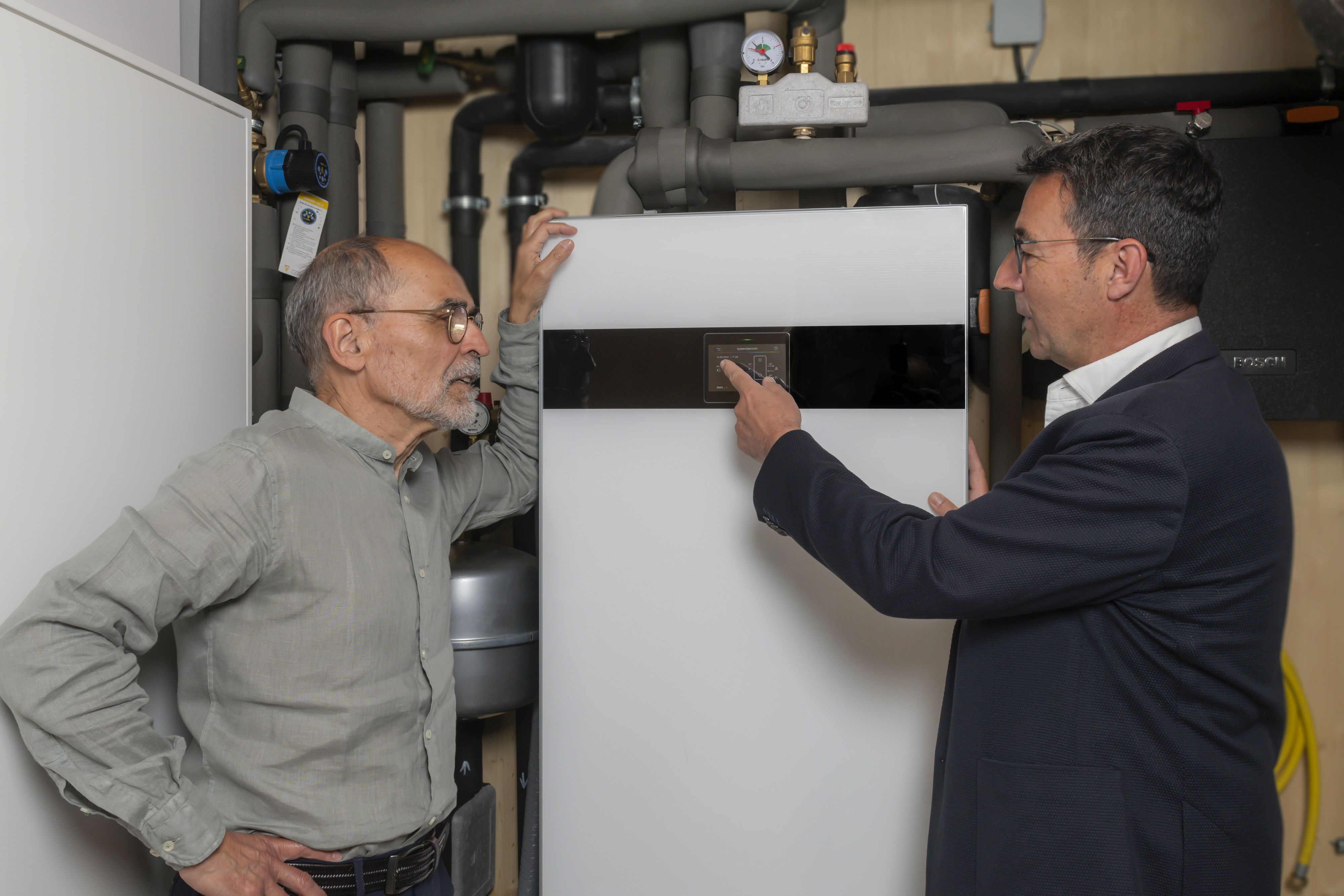 Zwei Männer stehen an der Inneneinheit einer Wärmepumpe